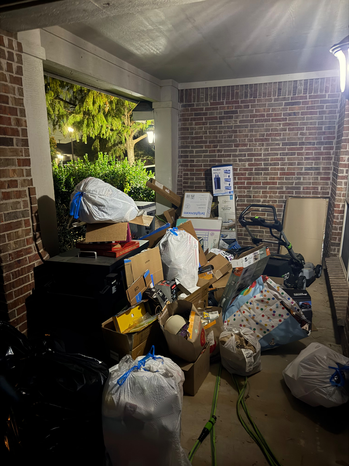 Before junk removal: covered patio in Burleson piled with boxes, trash bags, and old household items